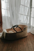 Baby Basket Natural and hypoallergenic mattress with Leather Handle in front of curtains