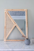 Squared Rattan Mirror next to concrete candle holder