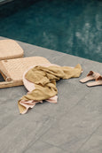 Thin Beach Blanket laying on floor next to slippers