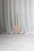 Carpet Beater in Rattan leaning against wall with curtains