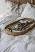 The Straw Changing Basket with Leather Handle on bed