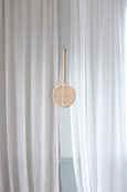 Carpet Beater in natural Rattan material hanging in middle of curtains